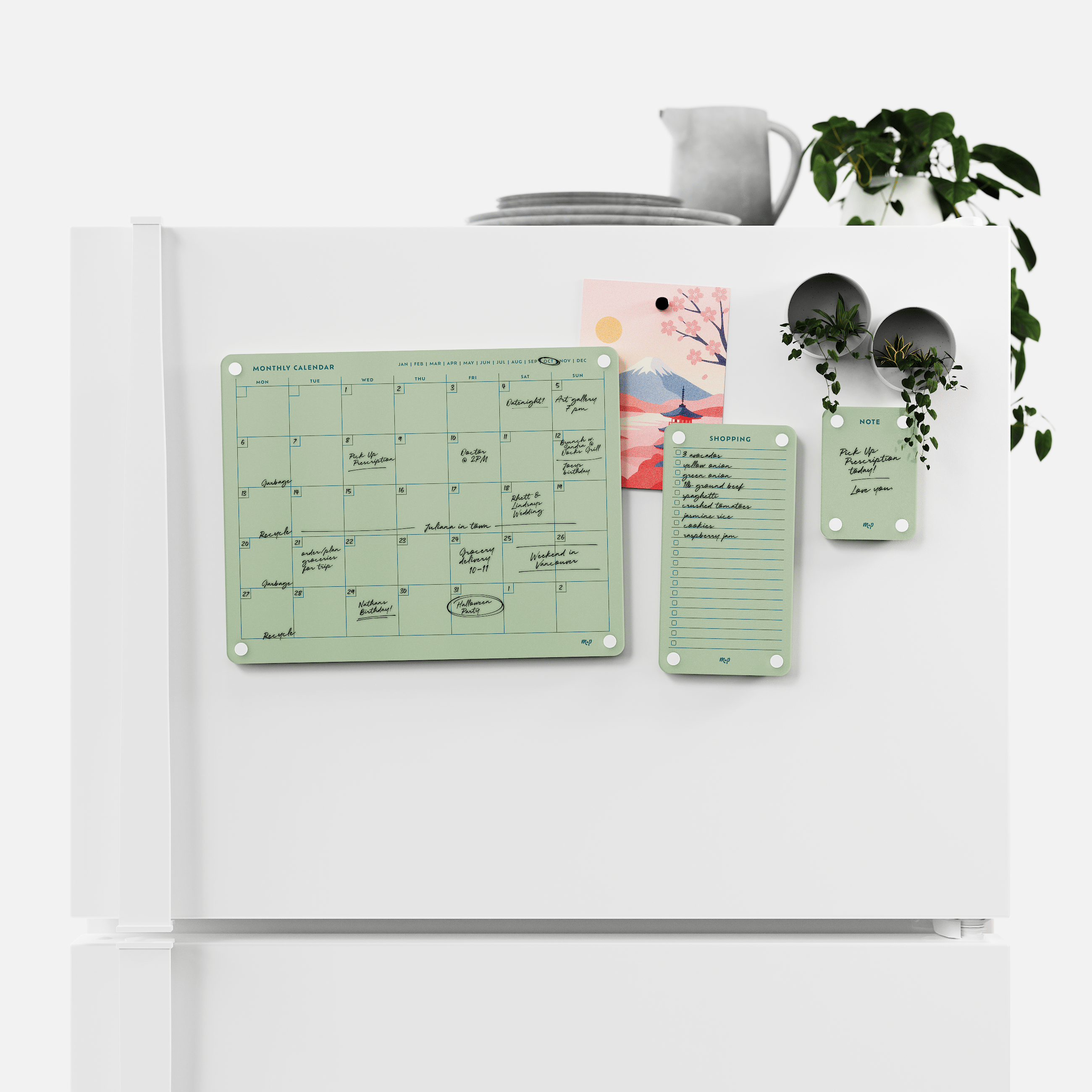 Matcha green monthly calendar, shopping list and note board magnetised to a white fridge door
